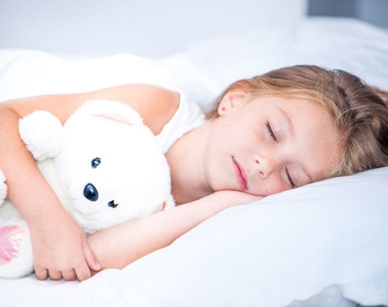 Child sleeping on pillow with white teddy