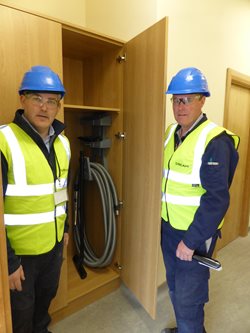 Beam engineers with central vacuum hose in Boliden Tara Mines office cupboard