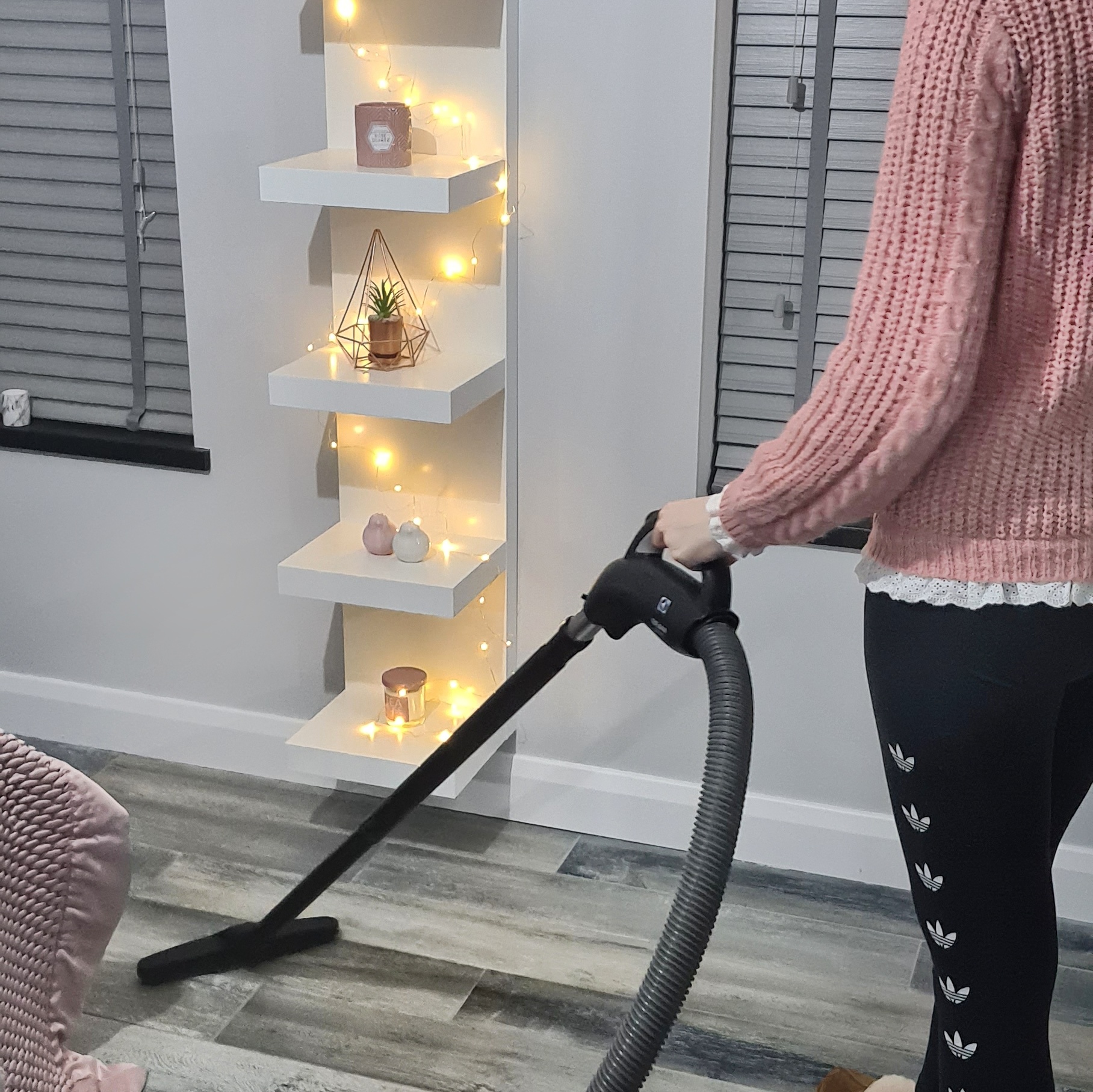 woman using Beam central vacuum on grey bedroom floor