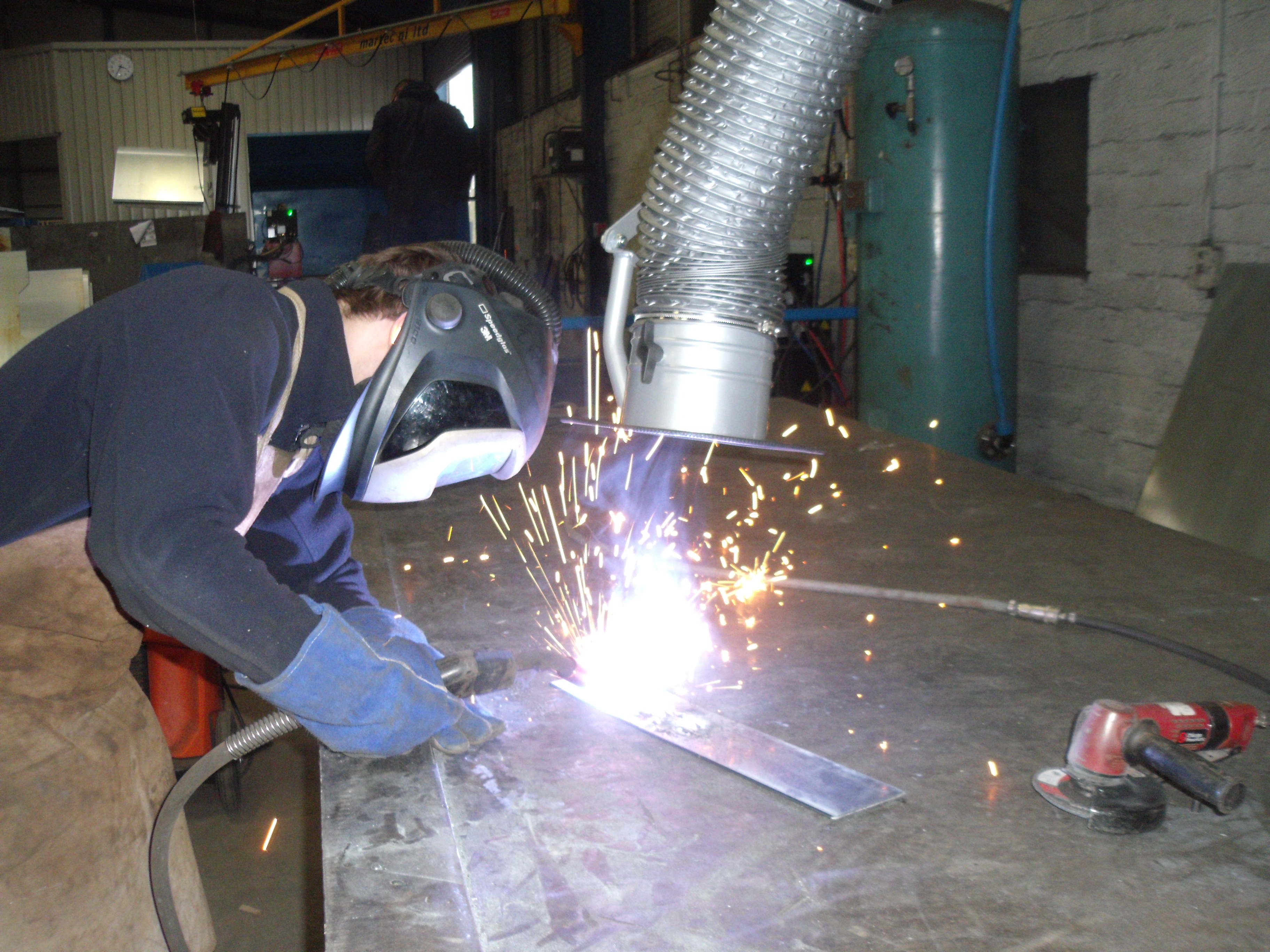 Weld fume extract arm in use by factory worker