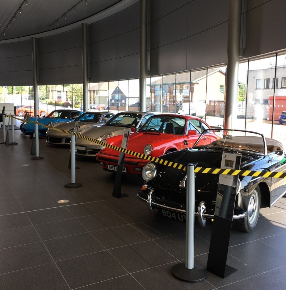 five vintage Porsche cars lined up in Porsche showroom
